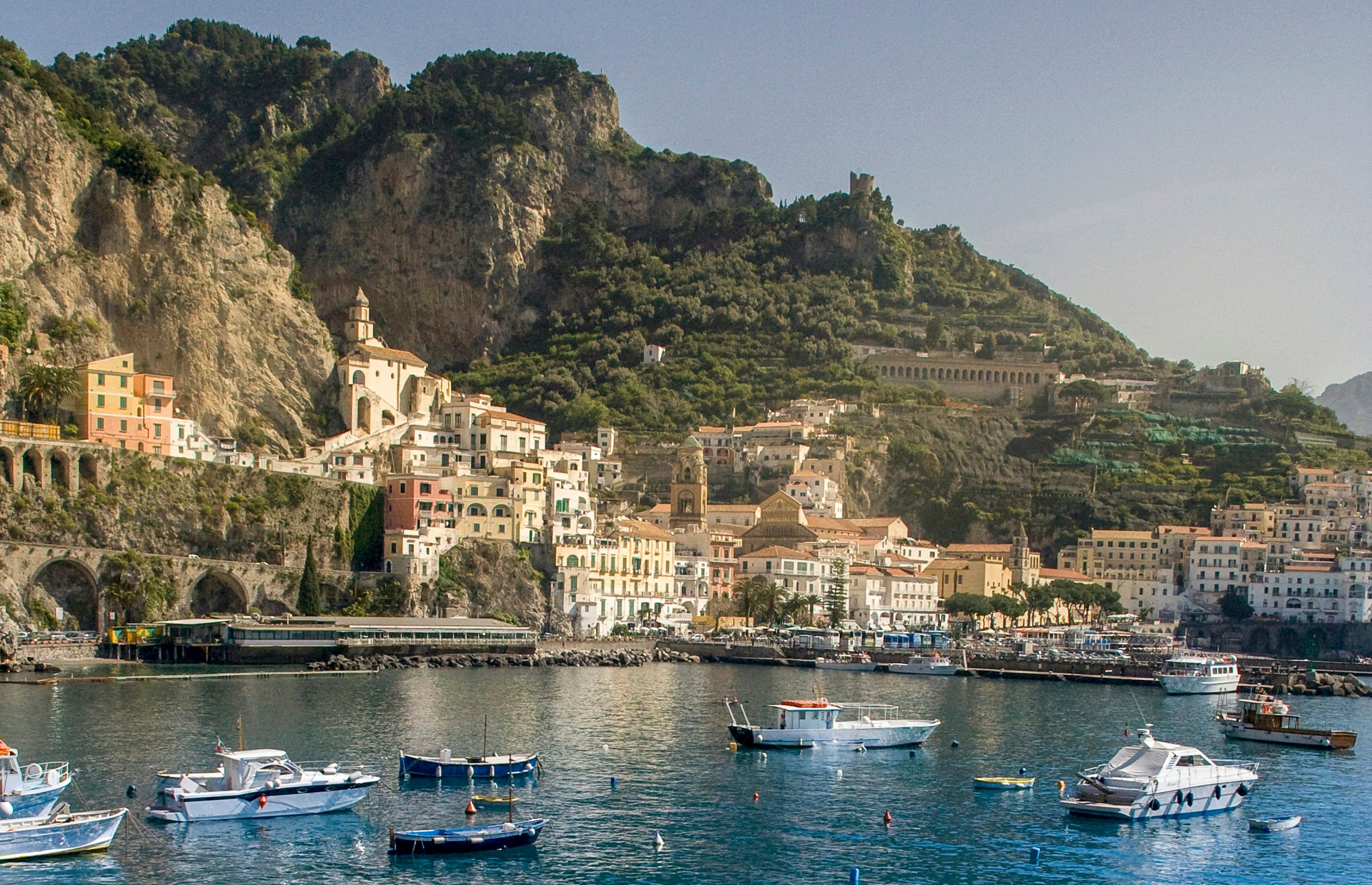 Fishing boats moored in the harbour below a cliffside town