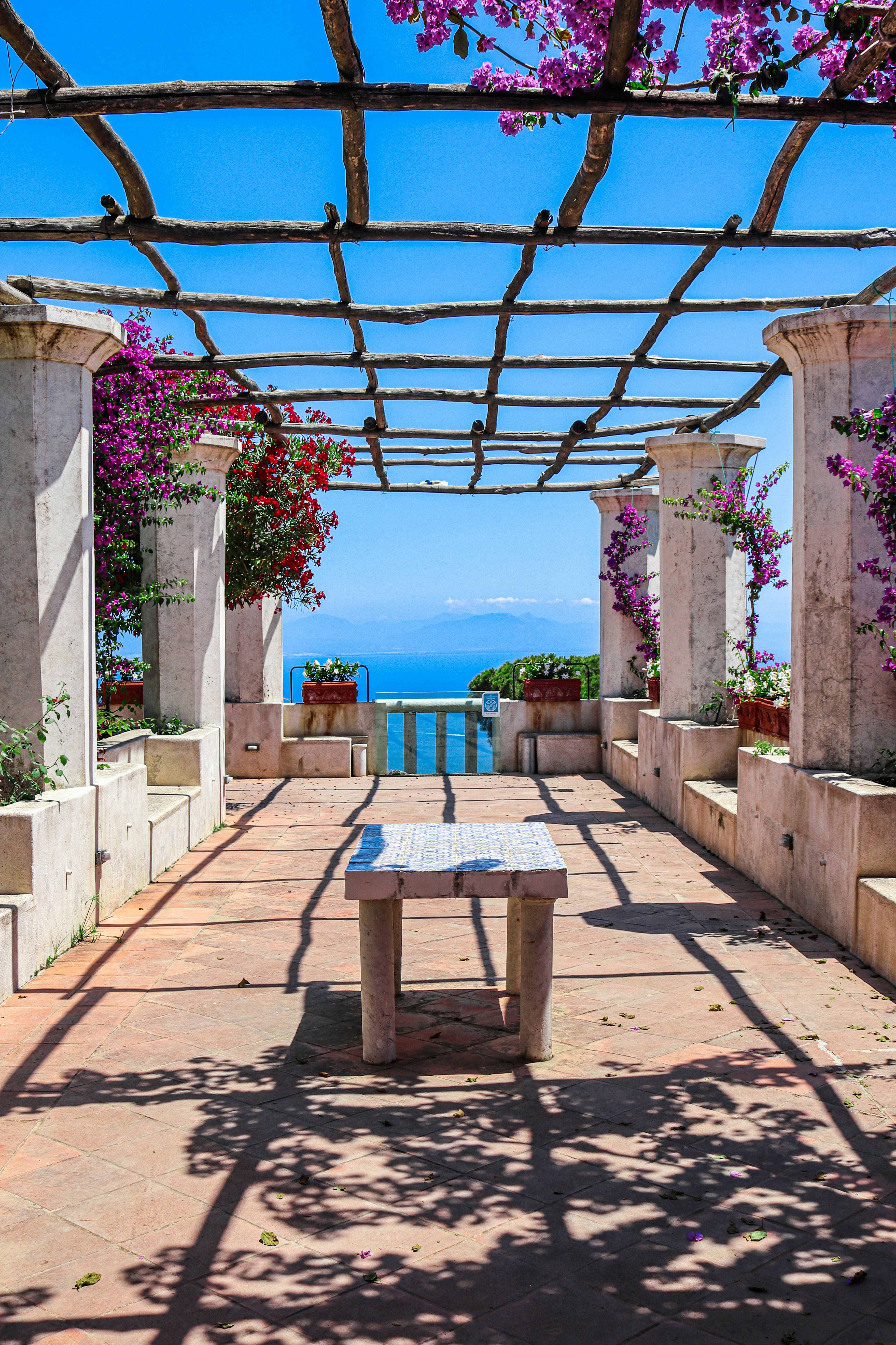 A bougainvillea pergola with a stone table, opening onto the sea